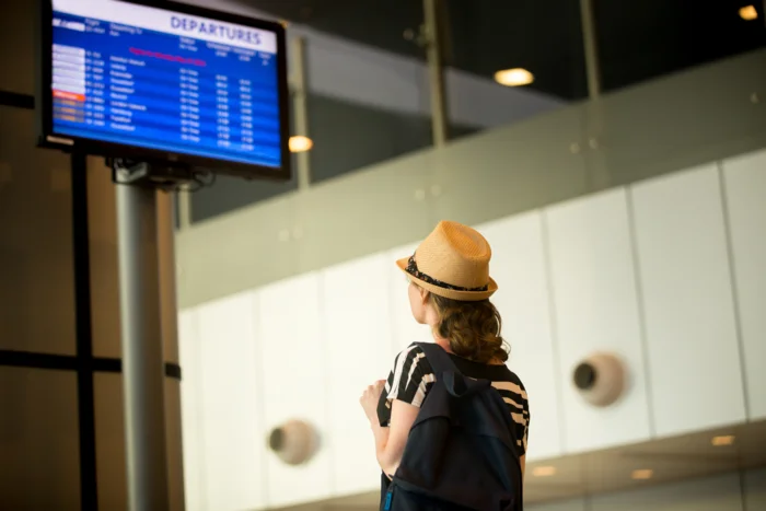 woman-front-airport-flight-information-panel